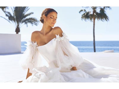 Noiva posando numa praia com um vestido tomara que caia com mangas bufantes em tule