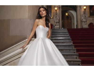Noiva posando numa escadaria com um vestido branco, liso e simples combinando com um cabelo longo e simples