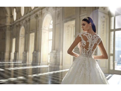 Noiva a posar de costas, apresentando os detalhes bordados do vestido de princesa rodado, combinado com uma tiara