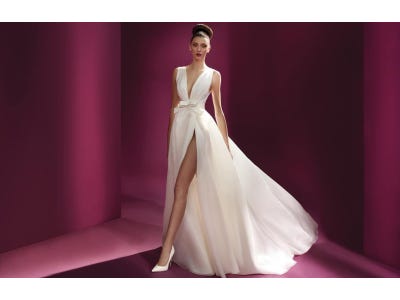 Noiva a usar um vestido branco de alças rodado com uma racha, coordenado com uns sapatos brancos de noiva de salto alto