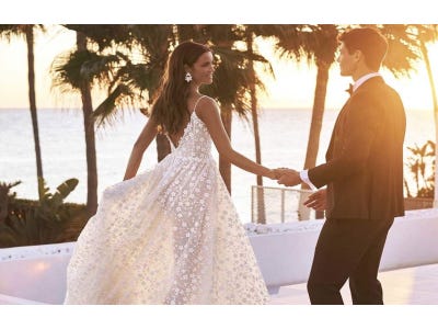 Un couple de mariés se tenant la main au coucher du soleil sur une plage. Une scène romantique et idyllique.