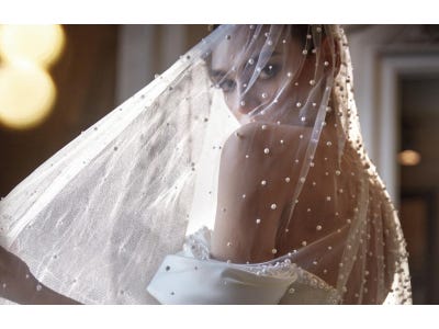 Woman wearing a beaded bridal veil and an off-the-shoulder wedding dress.