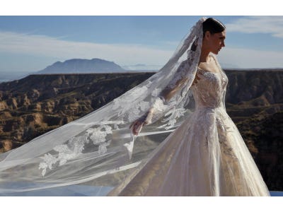 Brunette wearing a princess-cut ballgown in glitter tulle, walking outside against a backdrop of mountains