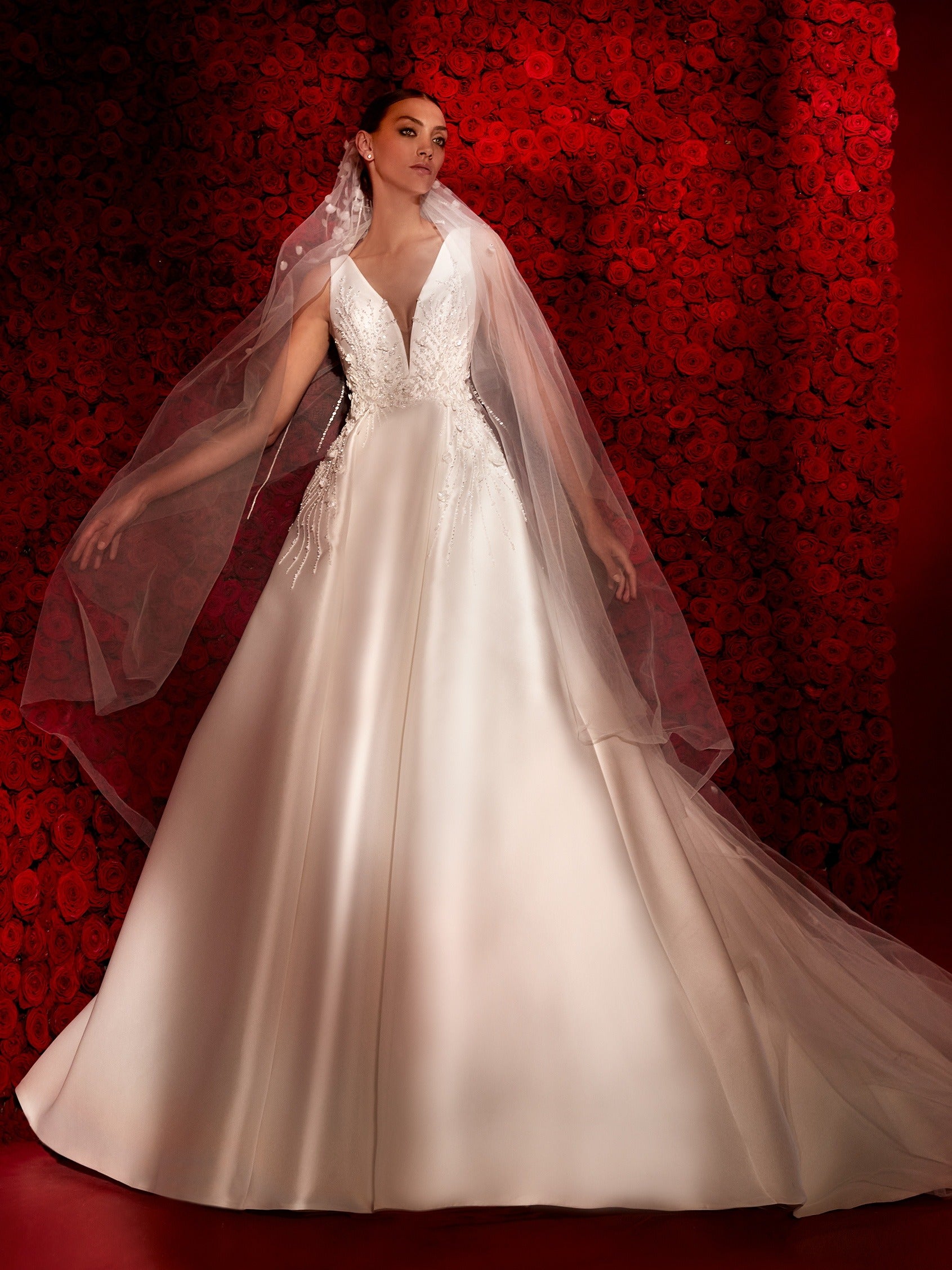 Ein präzis figurbetontes Brautkleid im Meerjungrau-Stil mit herrlich floriden Schmucksteinen. Der Meerjungfrau-Rock ist unterhalb des Knies ausladend und fließt traumhaft herab.