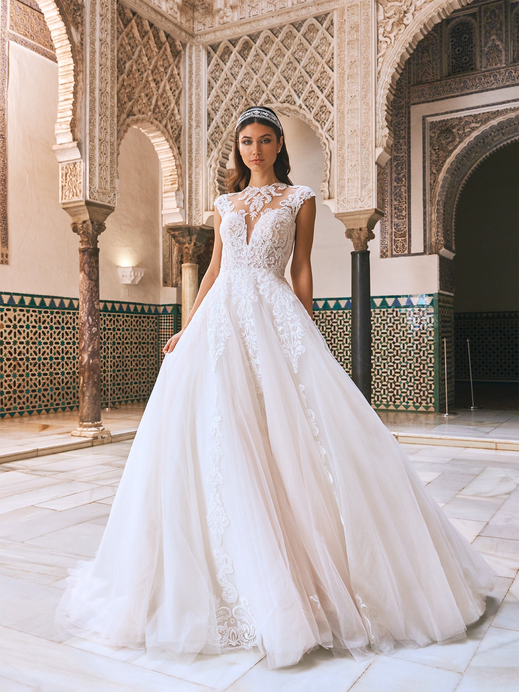 Die perfekte Ballkleid-Silhouette wird zum ultimativen Hochzeitskleid. Mit einem perfekt geformten, trägerlosen Oberteil, sinnlicher Peek-a-Boo-Spitze auf dem Rücken, einem bestickten Tüllrock und einer Schleppe, die einer Königin angemessen ist. 