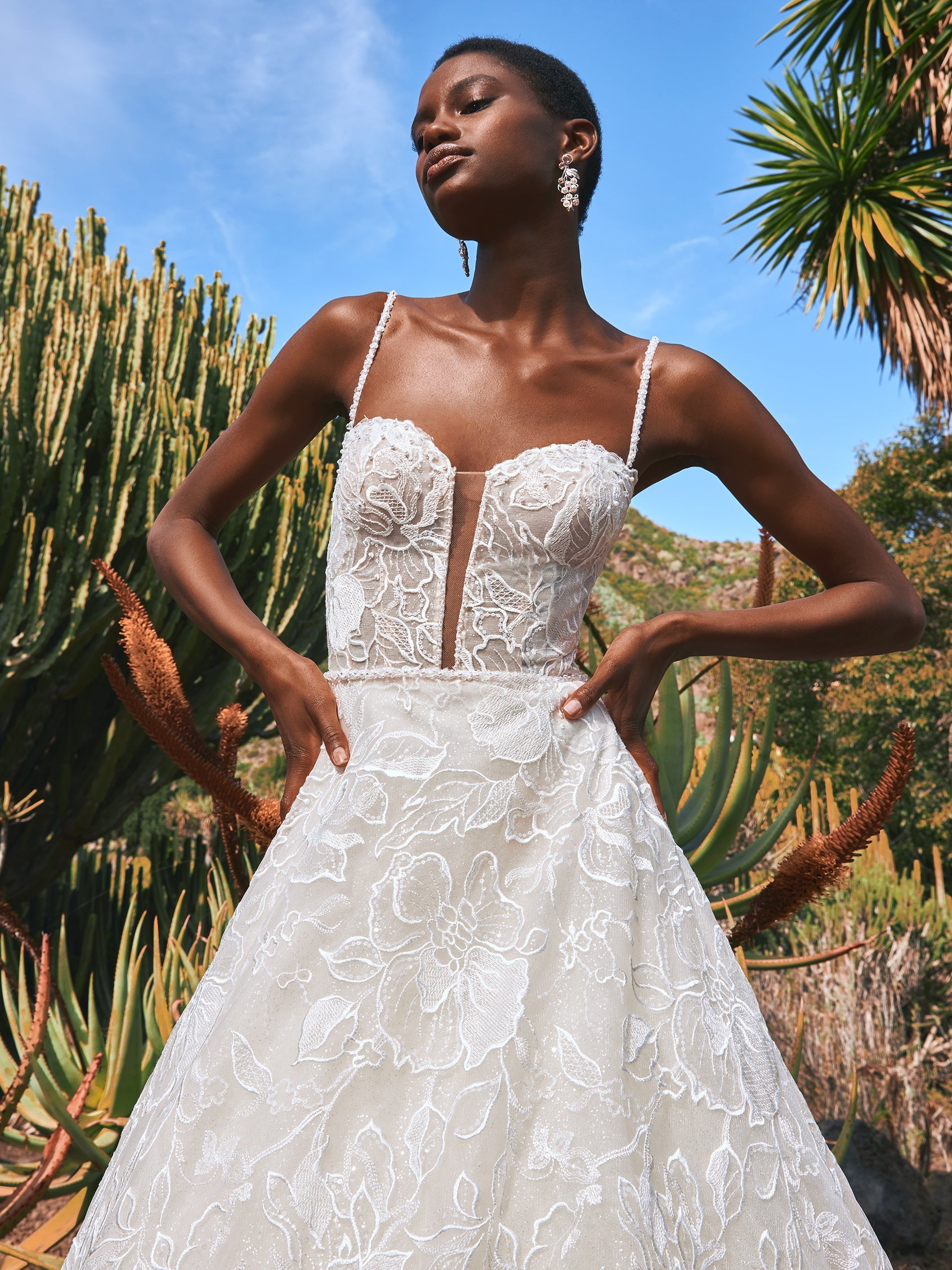 Cremefarbenes, schulterfreie Brautkleid aus weichem Tüll mit zarten Spitzenapplikationen in Form von Blütenblättern, die über die Corsage mit herzförmigem Dekolleté und den eleganten Rock im Prinzessin-Stil gestreut sind. 