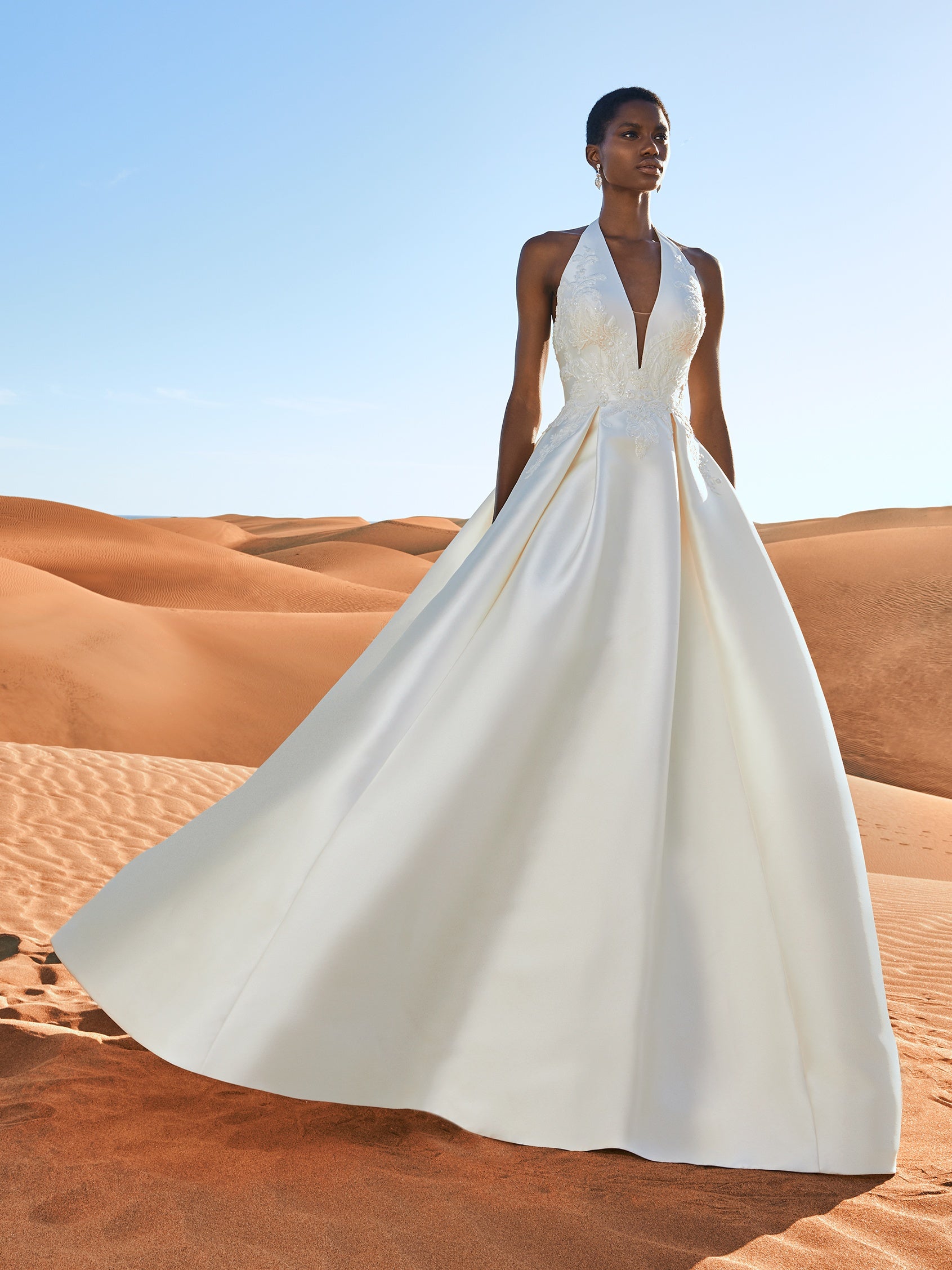 Cremefarbenes, schulterfreie Brautkleid aus weichem Tüll mit zarten Spitzenapplikationen in Form von Blütenblättern, die über die Corsage mit herzförmigem Dekolleté und den eleganten Rock im Prinzessin-Stil gestreut sind. 