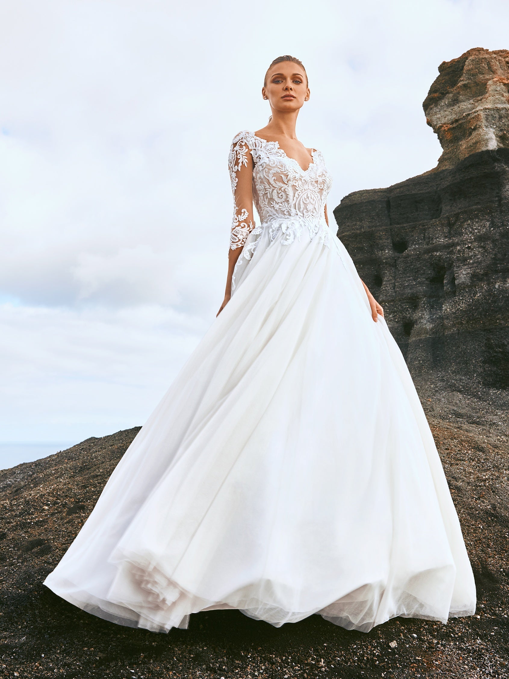 Cremefarbenes, schulterfreie Brautkleid aus weichem Tüll mit zarten Spitzenapplikationen in Form von Blütenblättern, die über die Corsage mit herzförmigem Dekolleté und den eleganten Rock im Prinzessin-Stil gestreut sind. 