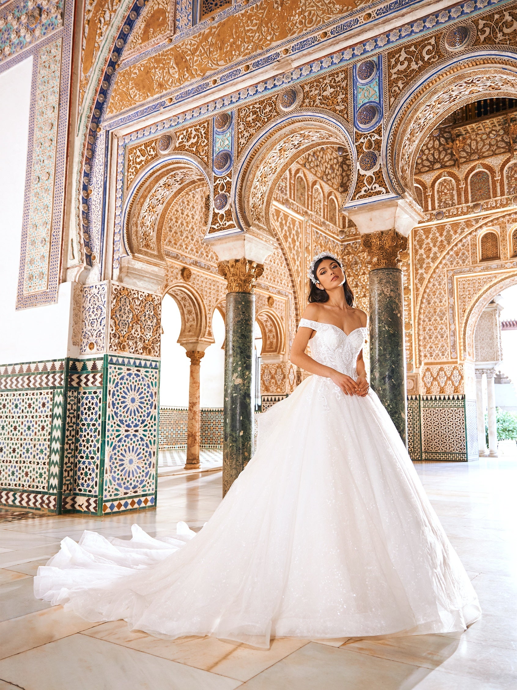 Die perfekte Ballkleid-Silhouette wird zum ultimativen Hochzeitskleid. Mit einem perfekt geformten, trägerlosen Oberteil, sinnlicher Peek-a-Boo-Spitze auf dem Rücken, einem bestickten Tüllrock und einer Schleppe, die einer Königin angemessen ist. 