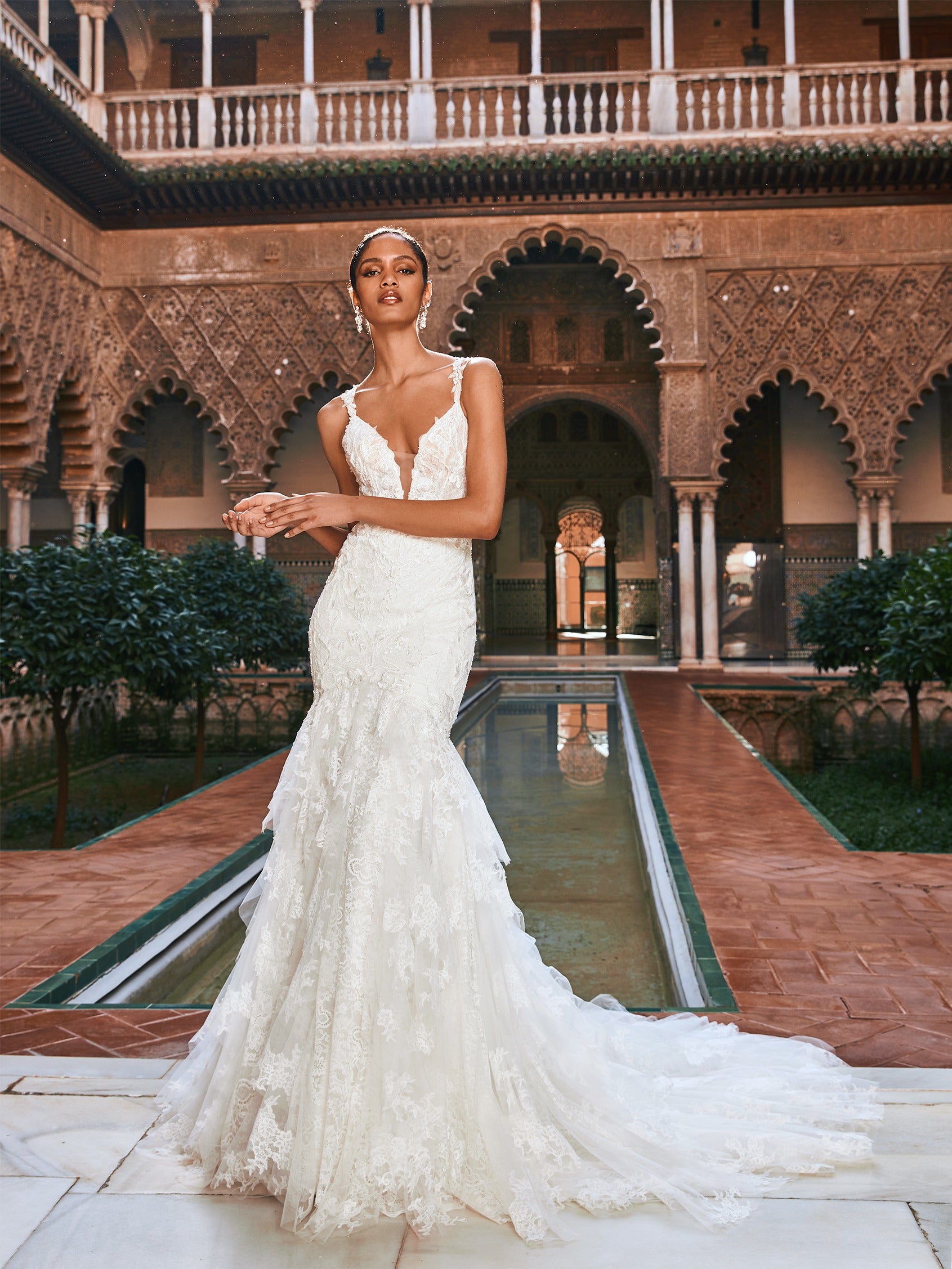 Ein in den 1920er Jahren inspiriertes Brautkleid mit ausgestelltem Rock aus handgefertigter Spitze fließt sanft über Rücken und Gesäß und wird durch eine prächtige Kapellenschleppe aus butterweichem Tüll abgerundet. Der Überrock sorgt für zusätzliches Volumen, damit der Gang zum Altar ein ganz besonderer Auftritt wird. 