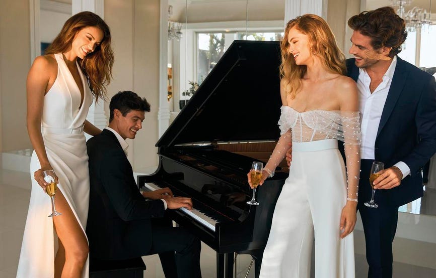 Dois casais a posar perto de um piano com roupas elegantes para uma cerimónia