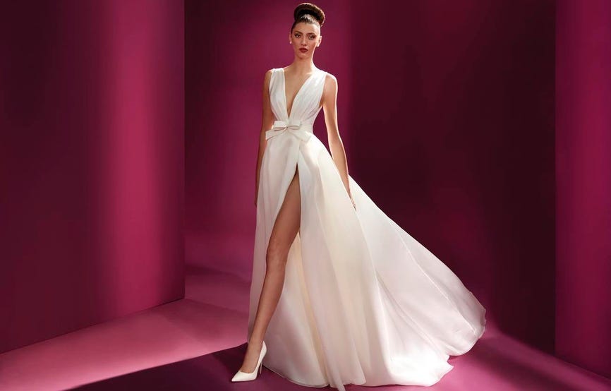Noiva a usar um vestido branco de alças rodado com uma racha, coordenado com uns sapatos brancos de noiva de salto alto