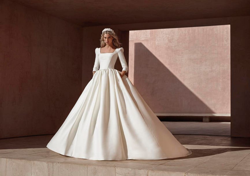 Imposante robe de mariée princesse blanche, au tissu fluide et à col carré.