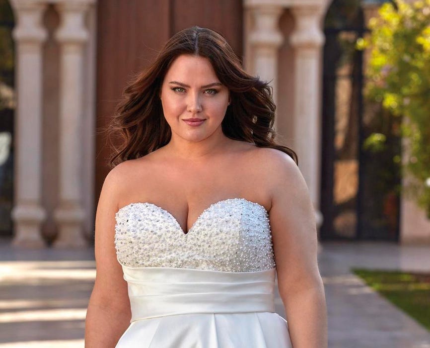 Woman with dark hair in a strapless plus size wedding dress with intricate details on the bodice. 