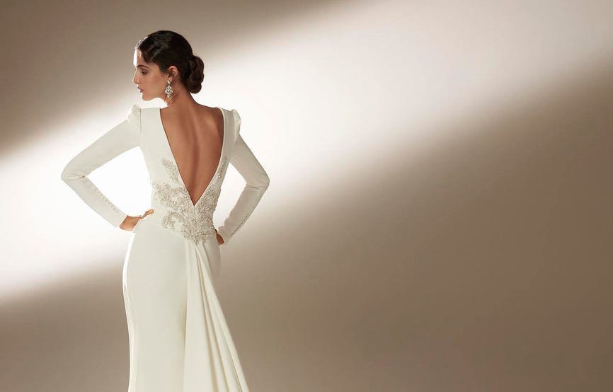 Modella di spalle che indossa un elegante abito da sposa a maniche lunghe con scollo sulla schiena