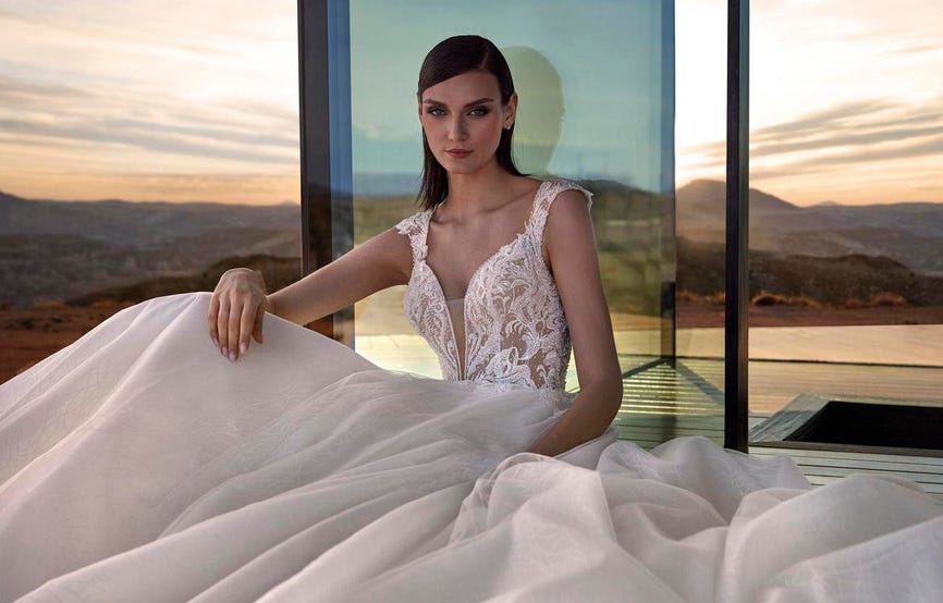 Νύφη φορώντας κομψό νυφικό σε άλφα γραμμή καθισμένη στο μπαλκόνι