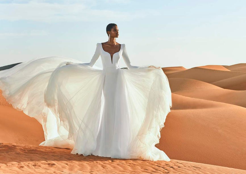 Une mariée dans une robe de mariée 2 en 1 d'une élégance simple, rehaussée d'une traîne fluide et d'un joli décolleté