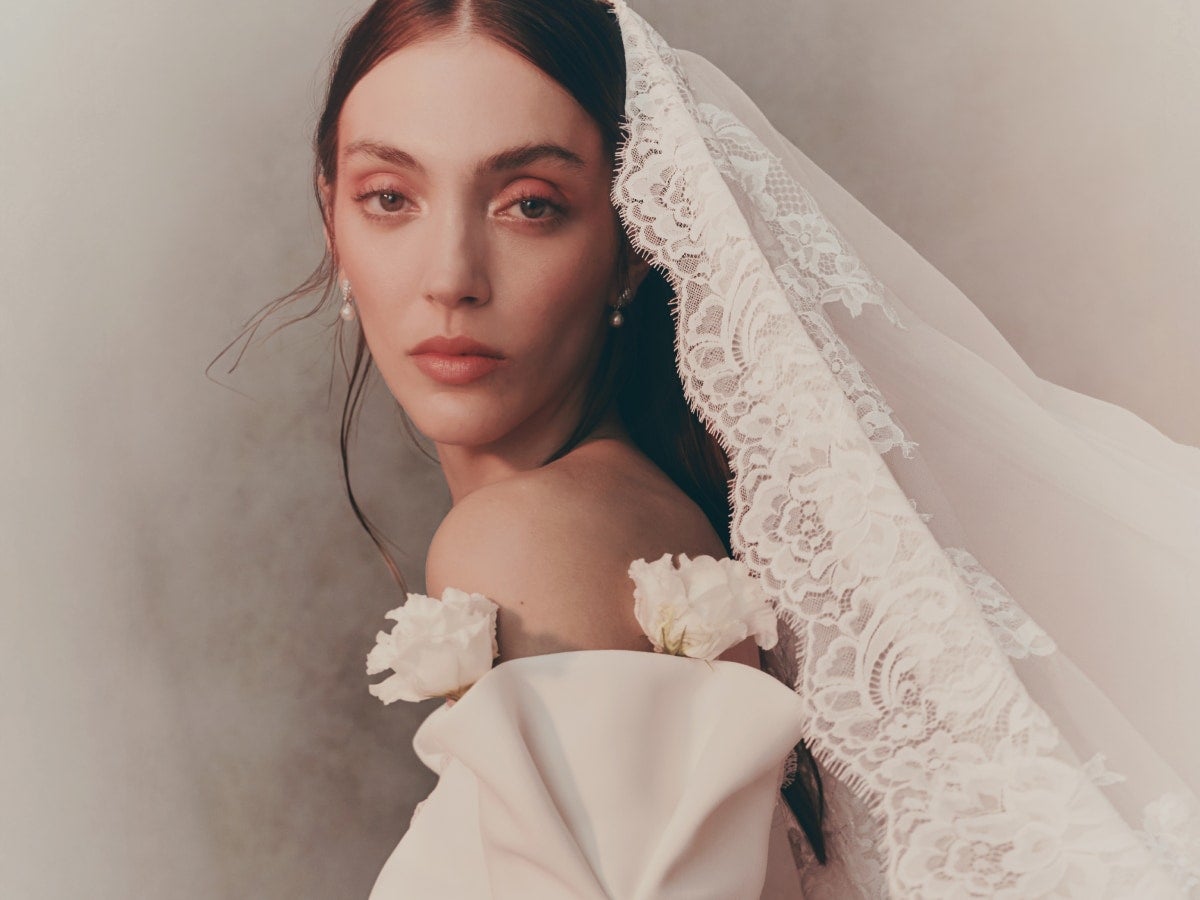 Mujer con un vestido de novia de pedrería y un tocado de novia para el pelo suelto y el cielo azul de fondo 