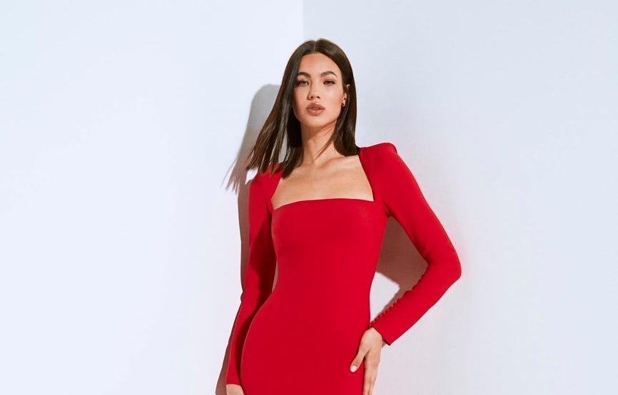 Brunette wearing a red high-neck mermaid party dress in crepe, looking straight ahead