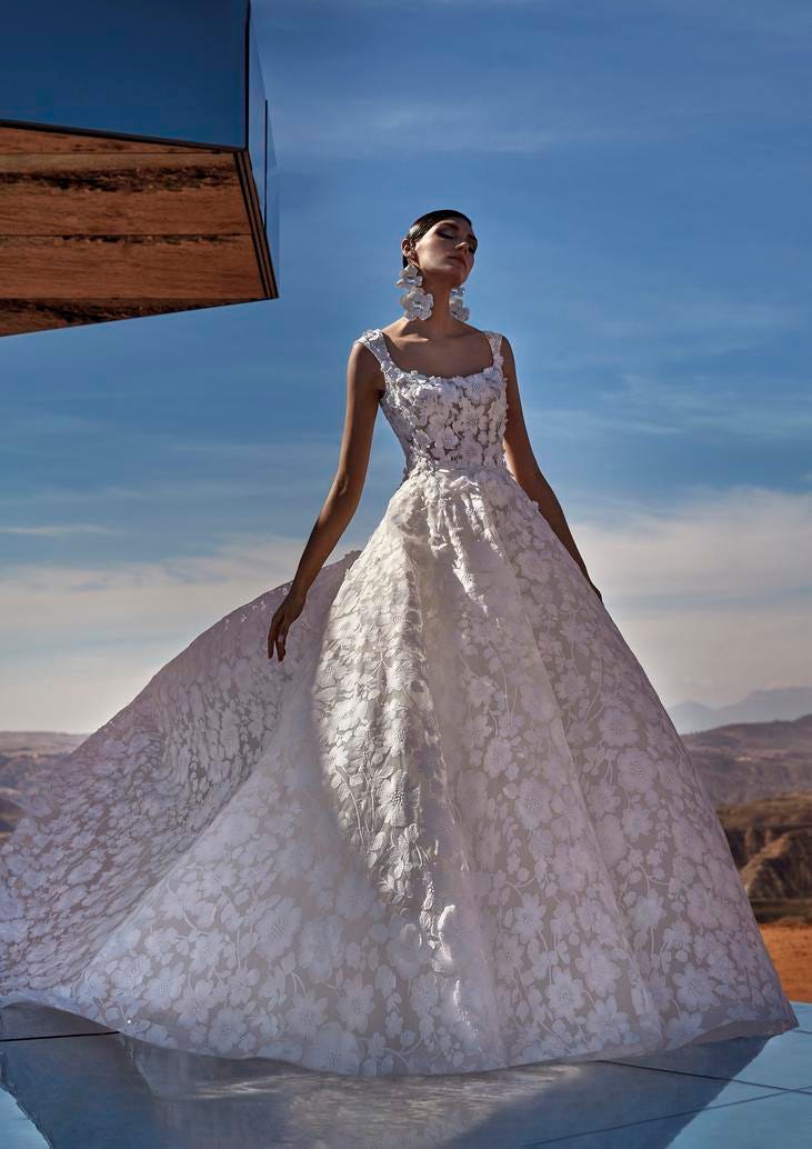 Modella che indossa un voluminoso abito da sposa in pizzo con ampia gonna e ricami floreali