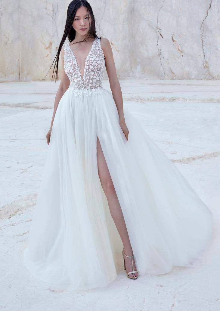 Mujer con un vestido de novia con transparencias, escote en V y una abertura en la falda con el pelo liso y suelto