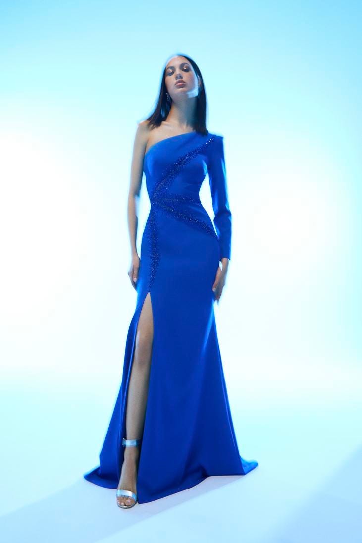 Mujer vestida de invitada de boda con un vestido azul rey con mangas largas 