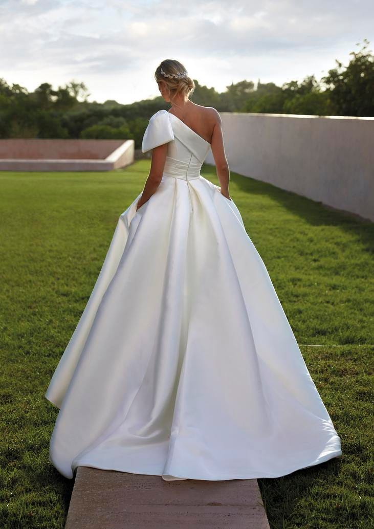 Noiva a posar de costas num cenário de natureza mostrando a beleza do sue vestido branco e minimalista