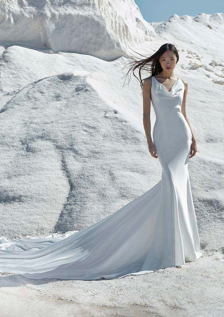 Mujer en un una montaña blanca con un vestido de novia color blanco con corte sirena