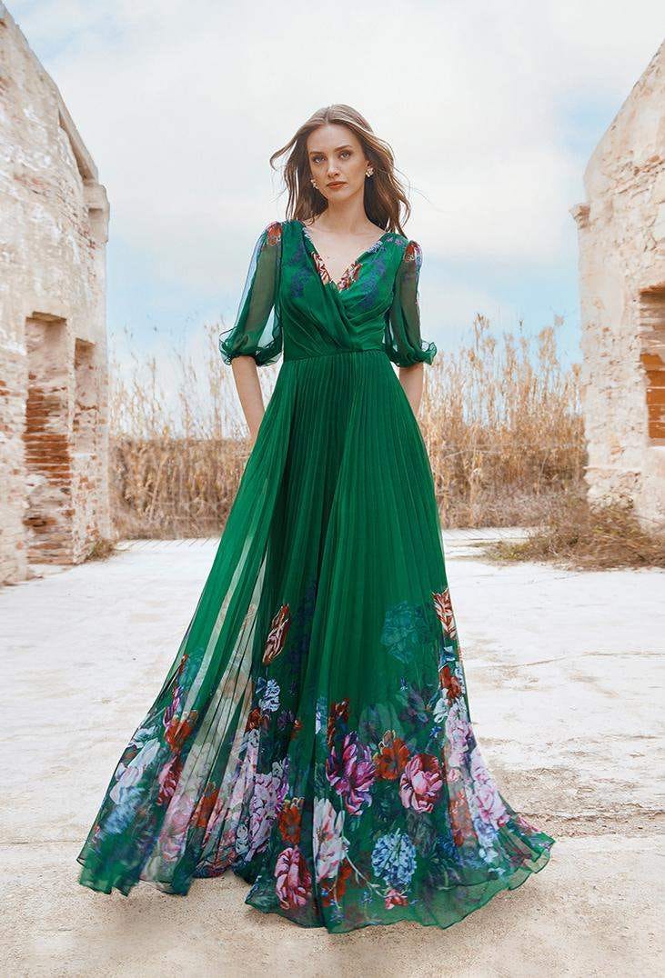 Une demoiselle d'honneur porte une robe verte à manches longues. Le col et le bas de la robe sont ornés de motifs floraux.