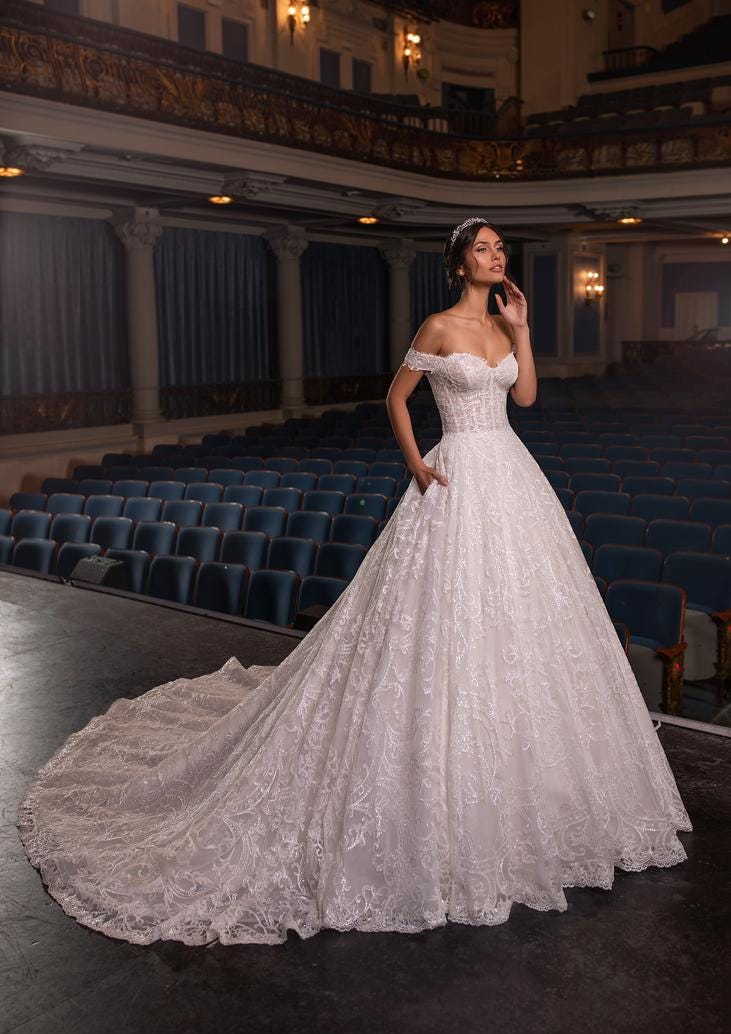 Dark-haired woman in an off-the-shoulder lace wedding dress.