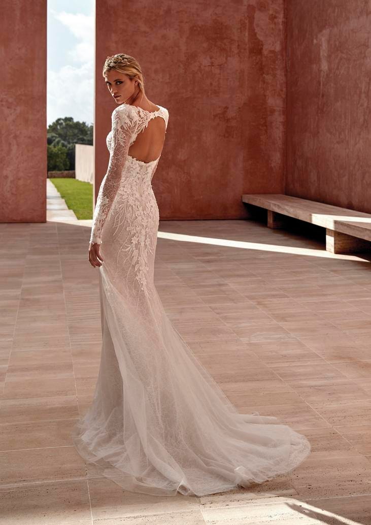 Blonde woman in lace long-sleeved wedding dress with open back and tulle train