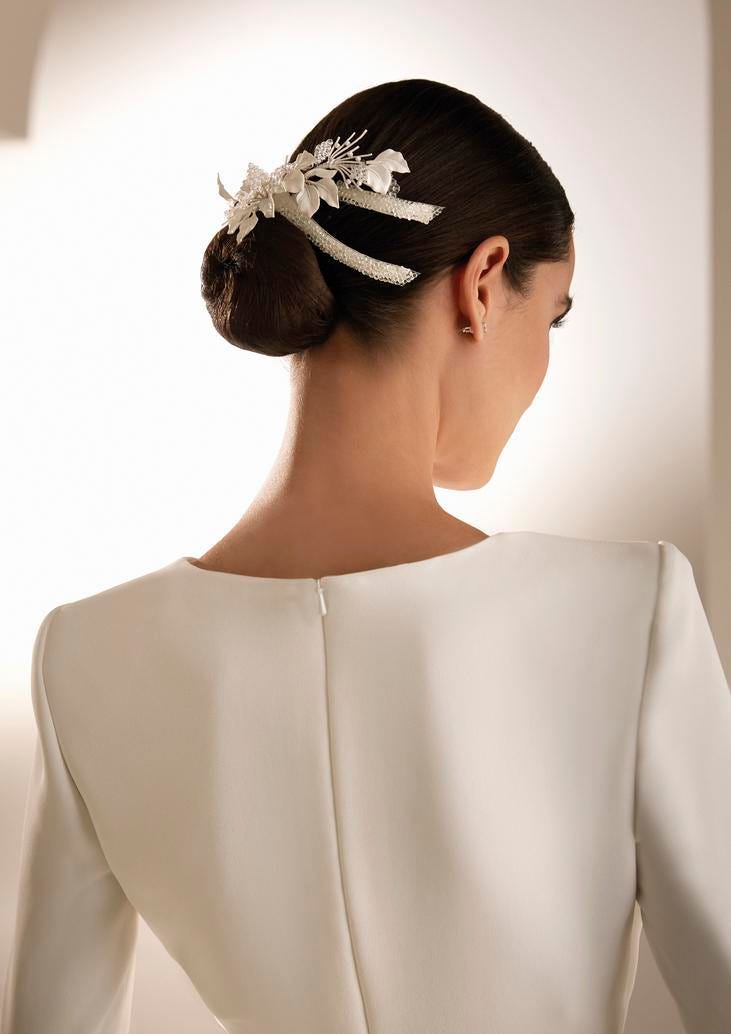 Noiva vestindo um vestido minimalista conjugado com um penteado simples de coque baixo com um grampo de flores