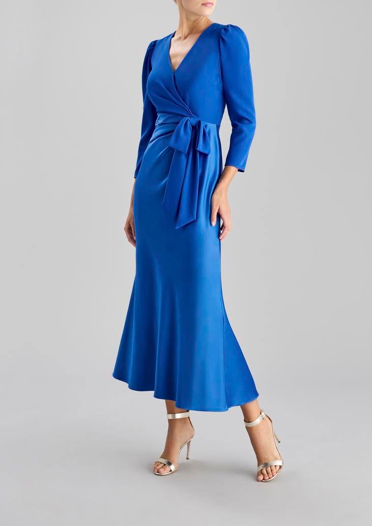 Convidada a usar um vestido longo e de mangas compridas azul com um decote em bico com um detalhe de laço na cintura