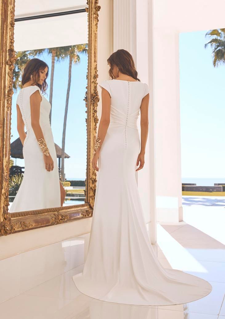 Mujer vestida de novia frente a un espejo probándose el vestido de novia