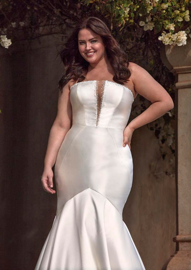 Donna che indossa un modello di abito da sposa plus size a sirena senza spalline.