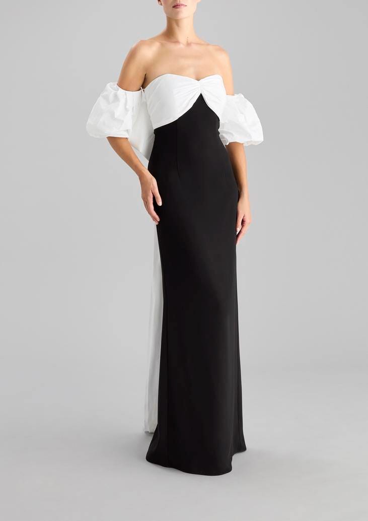 Kobieta prezentująca długą suknię na wesele z bufiastymi rękawami w kolorze białym oraz prostym dołem w kolorze czarnym