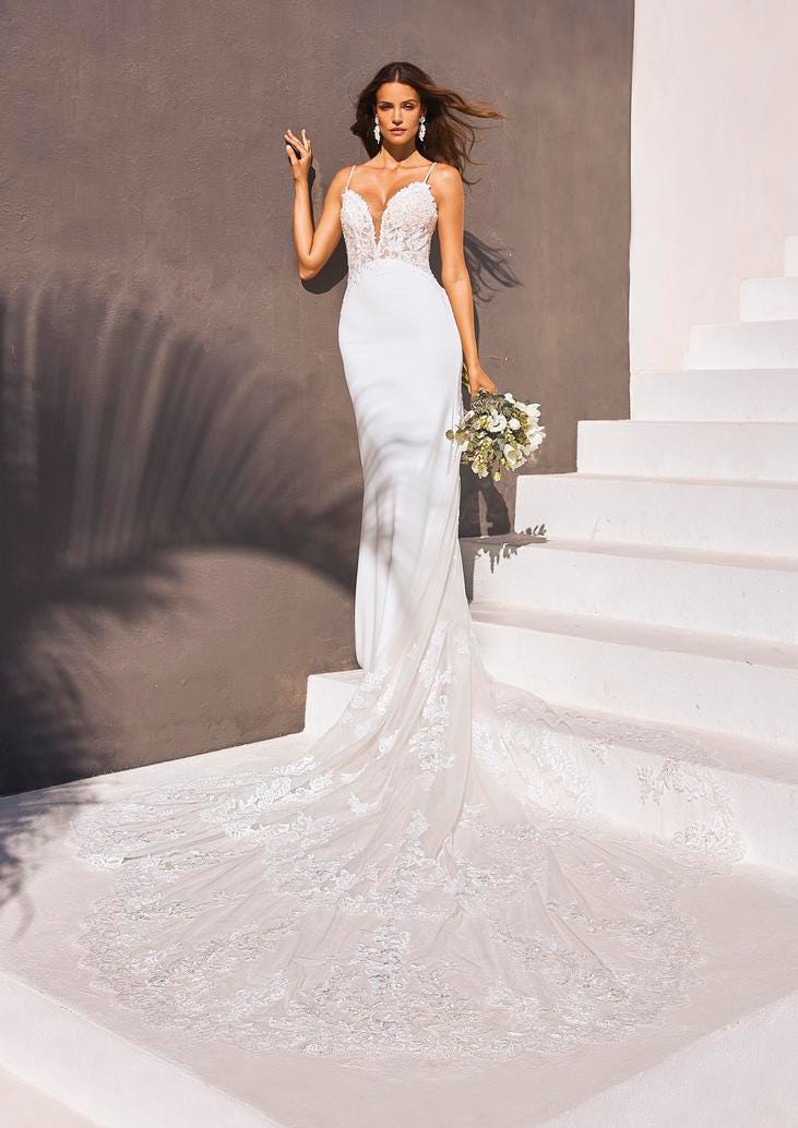 Panna młoda pozująca na schodach ubrana w długą suknię ślubną trzymająca w ręku ślubny bukiet