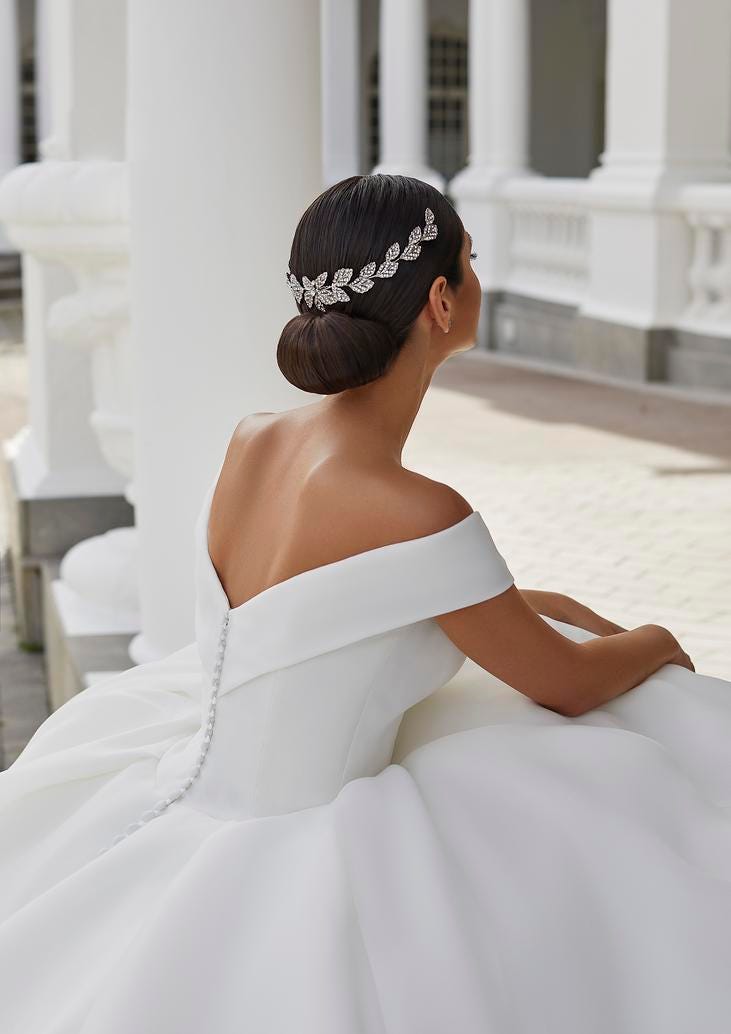 Close-up of a bride's elegant updo featuring a glittering leaf-patterned hairpiece, embodying sophistication.