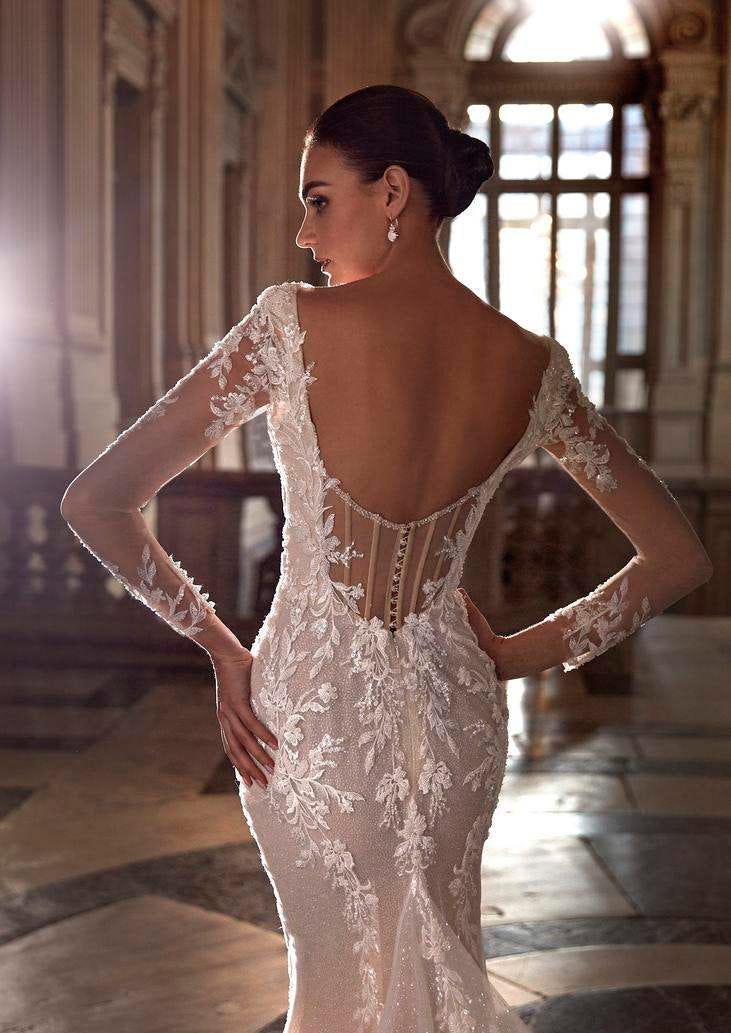 Mujer con un vestido de novia con transparencias y encaje de espaldas mirando hacia un lado
