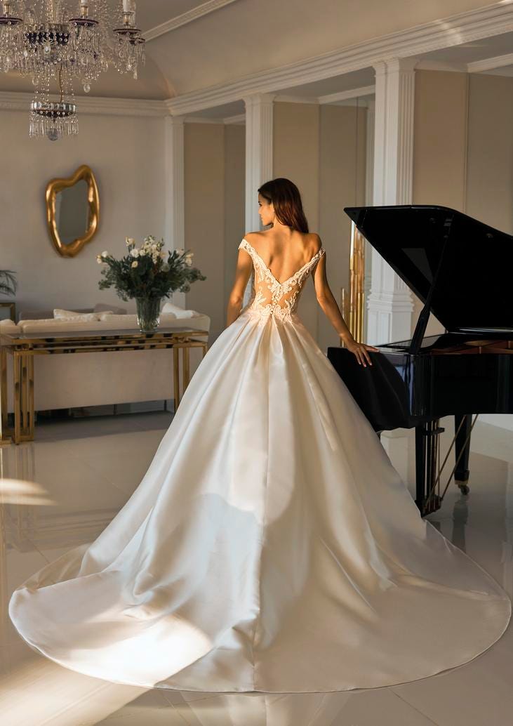 Mujer vestida de novia de espaldas, junto a un piano como decoración de su boda