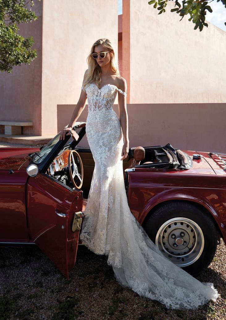 Une ravissante femme blonde dans une robe de mariée bustier ornée de motifs de dentelle avec traîne. 