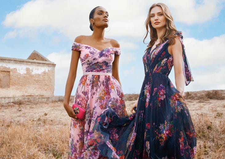 Dwie kobiety stojące w plenerze prezentują długie suknie w kwiatowe wzory idealne dla gości weselnych