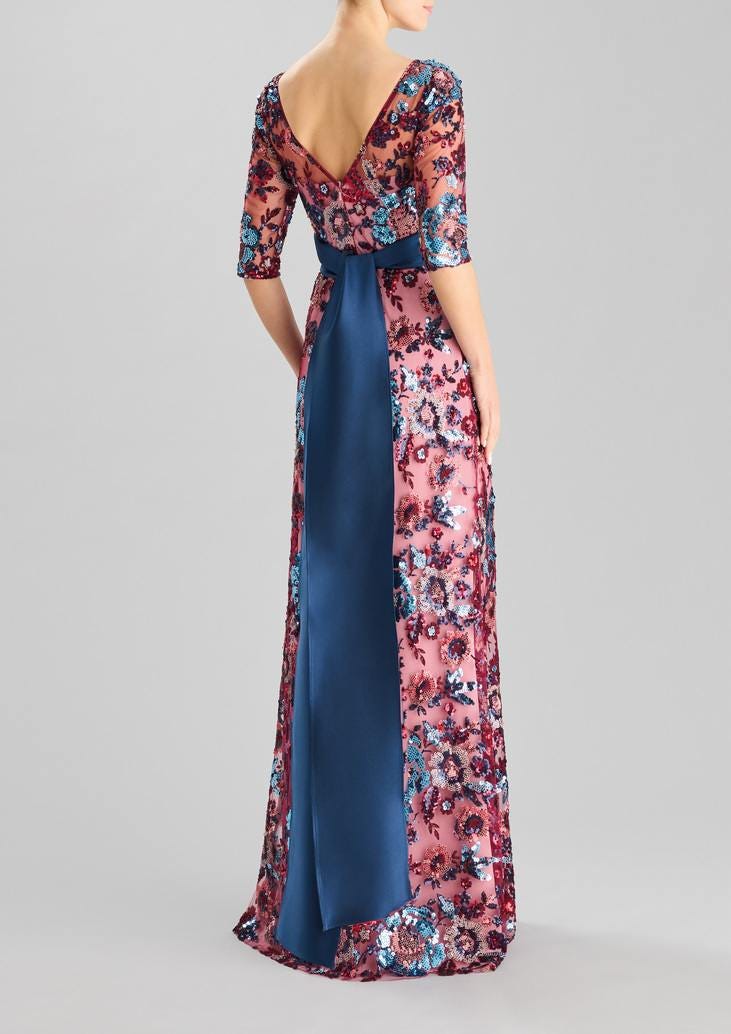 Mulher posando de costas com o seu vestido floral longo adornado com um cinto azul fluido
