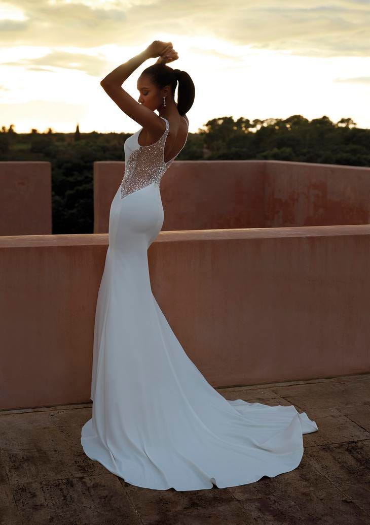 Donna di spalle su un terrazzo al tramonto con vestito da sposa a sirena, spalline e busto glitterato semi trasparente