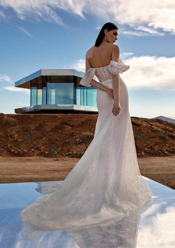 Modella di spalle che indossa un abito da sposa lungo con spalline cadenti e strascico