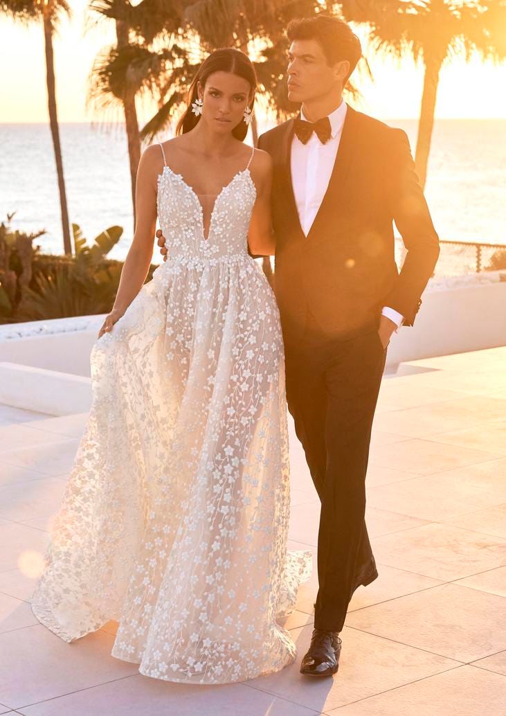 Coppia di sposi al tramonto che passeggia ed entrambi indossano i loro eleganti abiti da matrimonio.