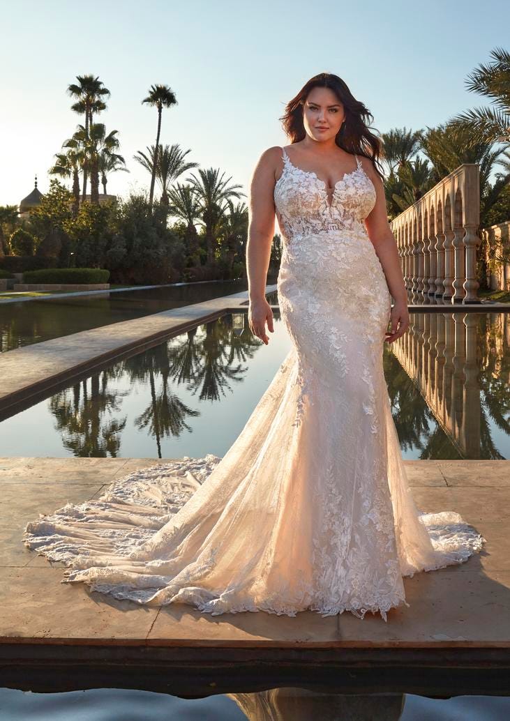 Woman in a plus size siren mermaid wedding dress in lace standing in front of a pool.