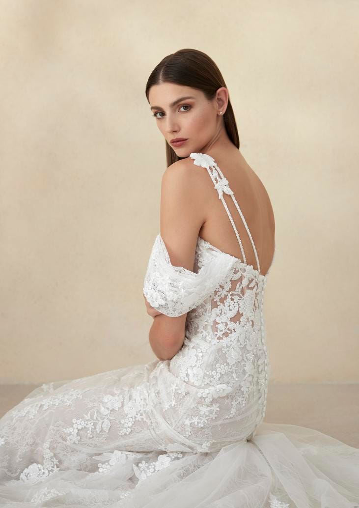 Dark-haired woman wearing a lace wedding dress with off-the-shoulder sleeves
