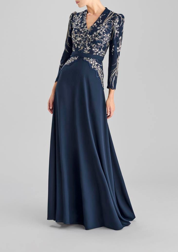 Woman wearing a navy A-line party dress with V-neck, three-quarter sleeves and intricate detailing