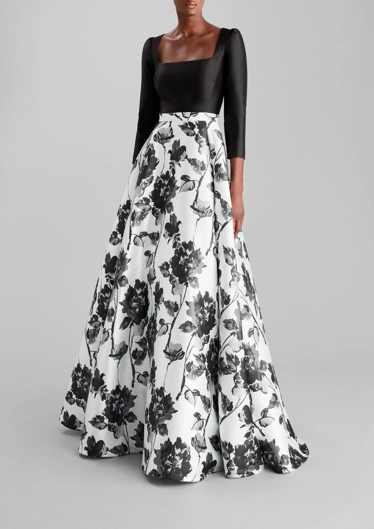 Woman wearing a long black and white princess-cut Mikado party dress with floral designs and square neckline